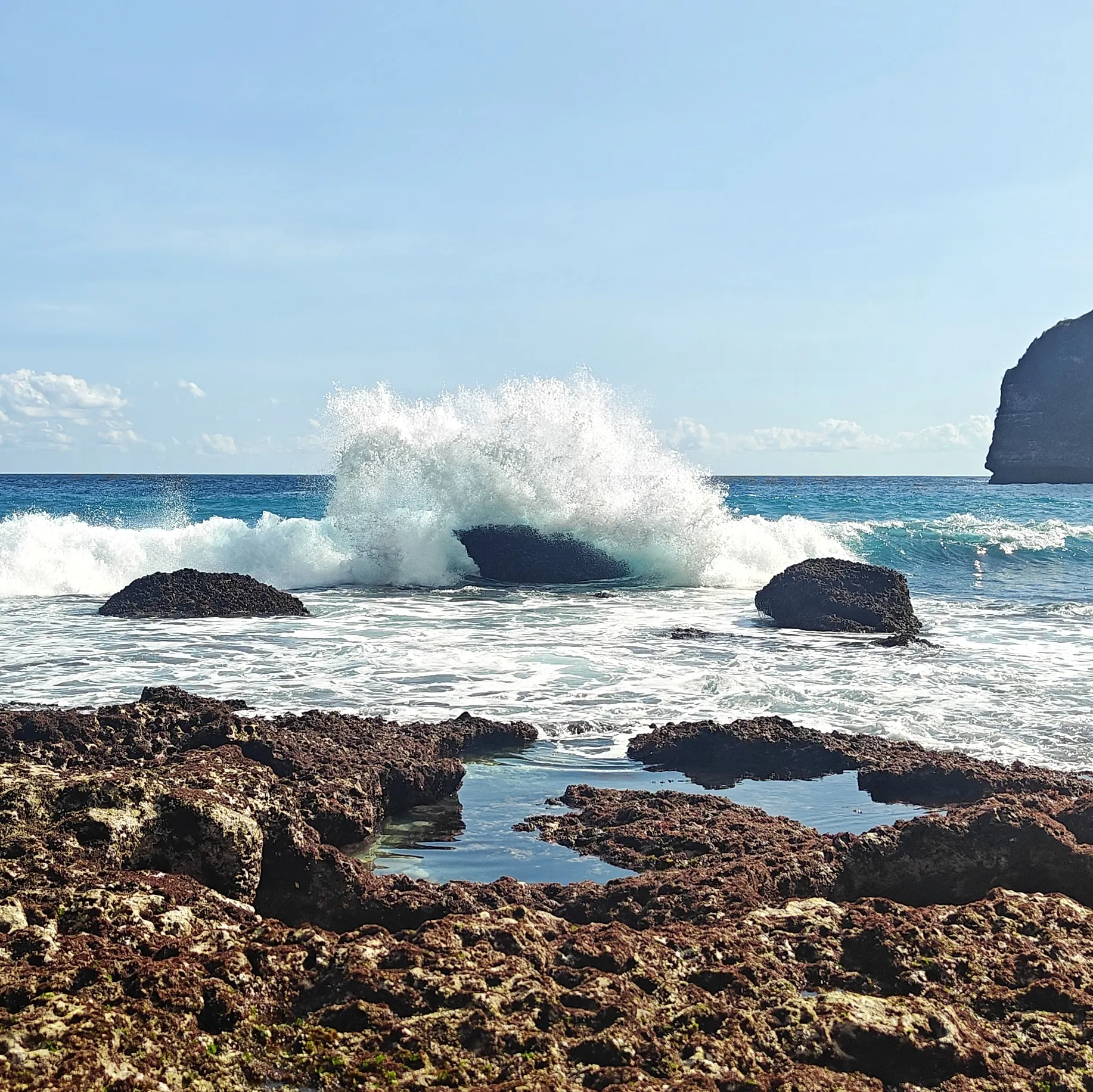a wave breaking over the rocks off the shore of tembeling beach